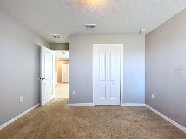 unfurnished bedroom with light carpet, a closet, and a textured ceiling