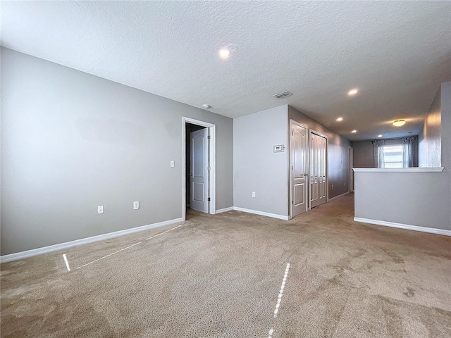 spare room featuring carpet and a textured ceiling