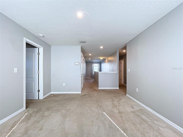 empty room with light carpet and a textured ceiling