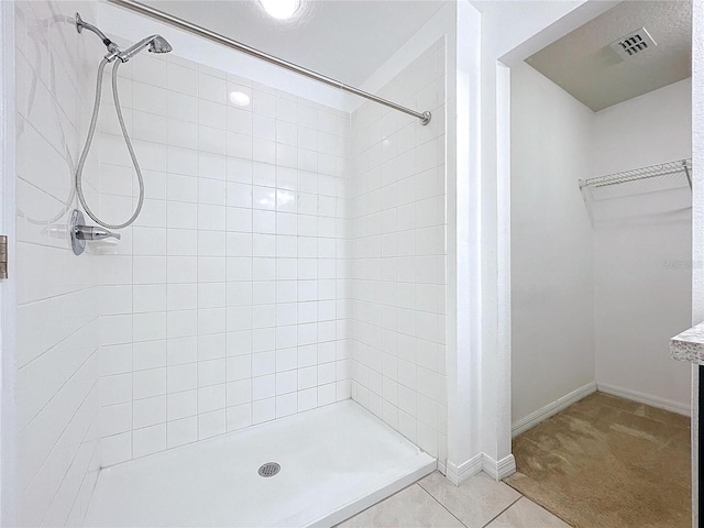 bathroom featuring tile patterned flooring and a tile shower