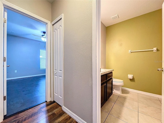 bathroom with hardwood / wood-style floors, vanity, ceiling fan, and toilet