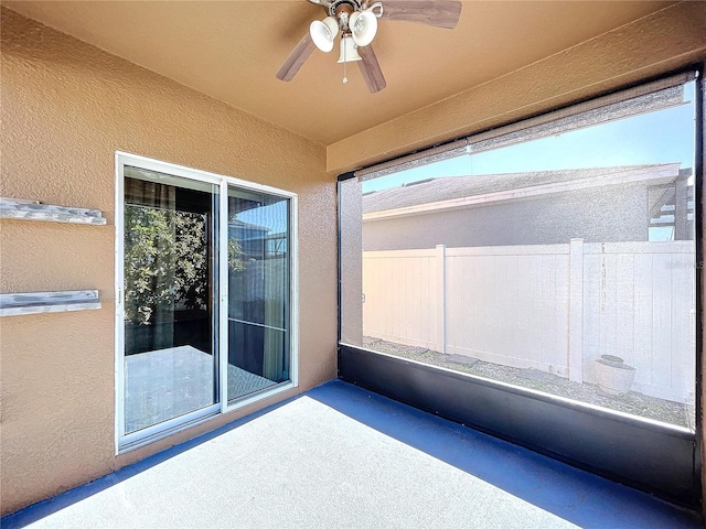 unfurnished sunroom with ceiling fan