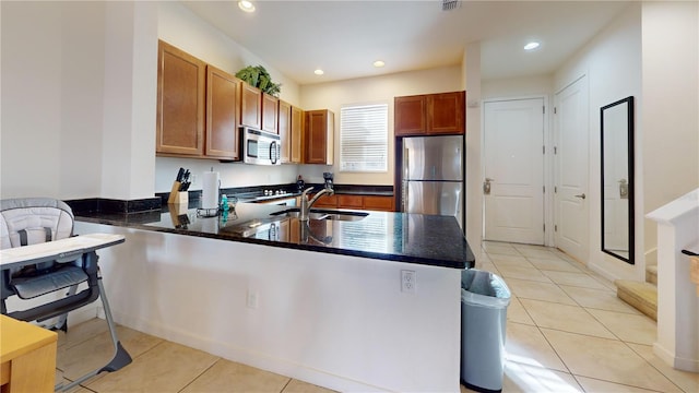 kitchen with kitchen peninsula, sink, light tile patterned floors, and stainless steel appliances