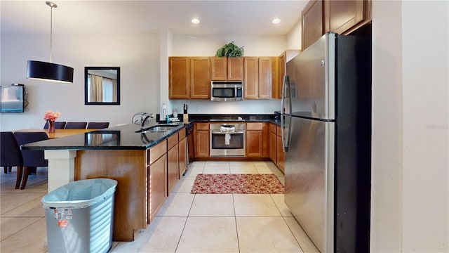 kitchen featuring kitchen peninsula, appliances with stainless steel finishes, sink, light tile patterned floors, and decorative light fixtures