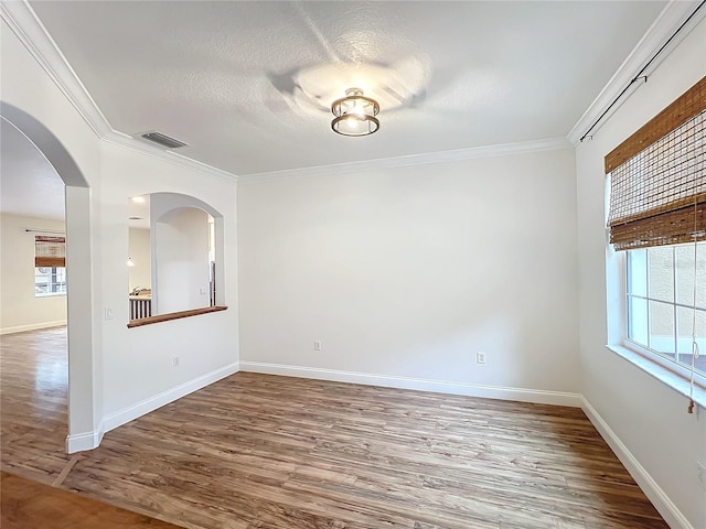 unfurnished room featuring a textured ceiling, hardwood / wood-style floors, plenty of natural light, and ornamental molding