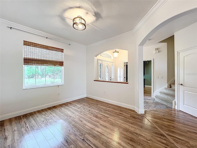 unfurnished room with wood-type flooring, a textured ceiling, and ornamental molding