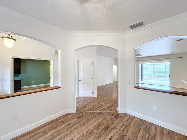 unfurnished room featuring hardwood / wood-style floors, crown molding, and a textured ceiling