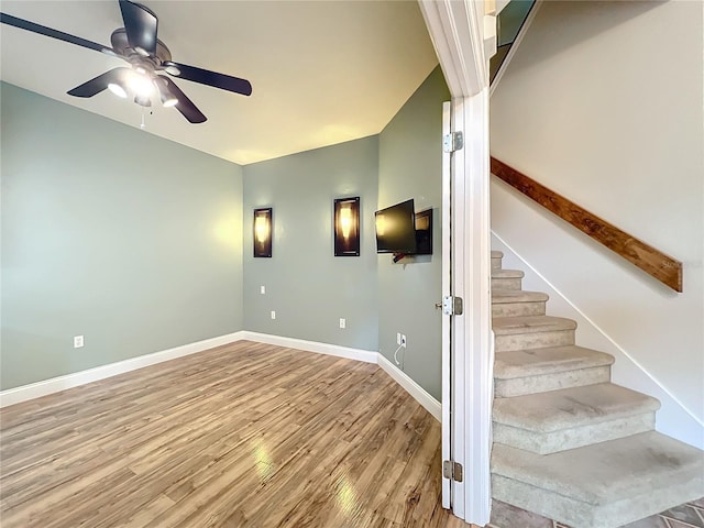 stairs featuring hardwood / wood-style floors and ceiling fan