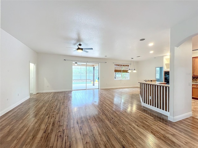 unfurnished living room with wood-type flooring, a textured ceiling, and ceiling fan