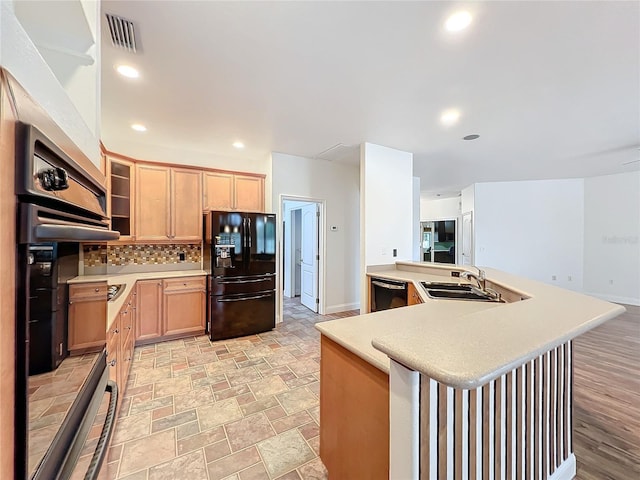 kitchen featuring light brown cabinets, black appliances, sink, decorative backsplash, and kitchen peninsula