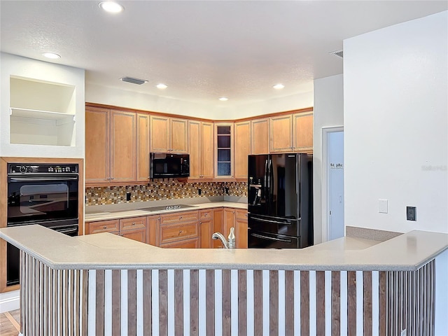 kitchen featuring kitchen peninsula, light wood-type flooring, backsplash, and black appliances