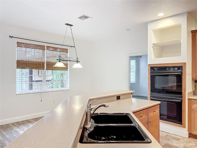 kitchen featuring hanging light fixtures, light hardwood / wood-style flooring, double oven, and sink