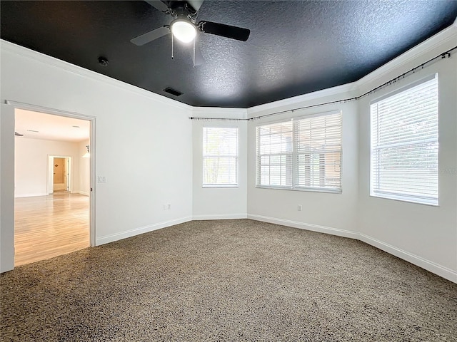 unfurnished room featuring a textured ceiling, carpet floors, ceiling fan, and crown molding