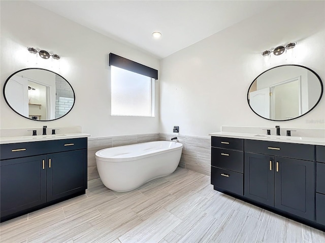 bathroom featuring a tub, vanity, and tile walls