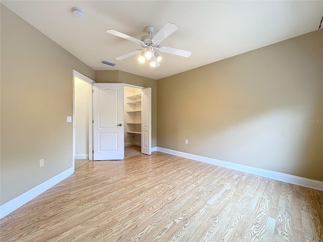 unfurnished bedroom featuring ceiling fan, light wood-type flooring, a spacious closet, and a closet