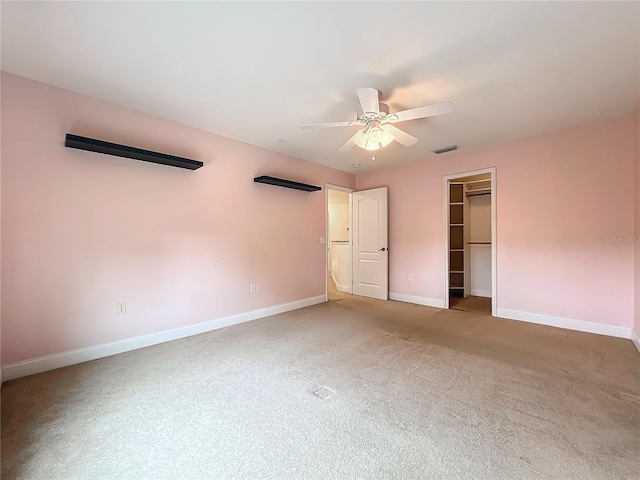 unfurnished bedroom featuring carpet, ceiling fan, a walk in closet, and a closet