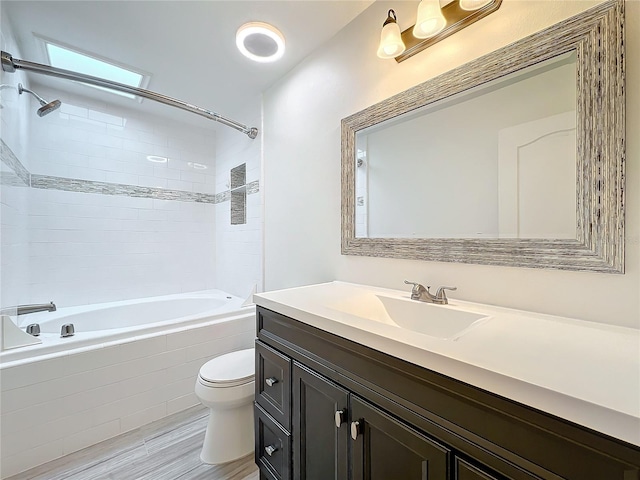 full bathroom featuring tiled shower / bath, vanity, wood-type flooring, and toilet