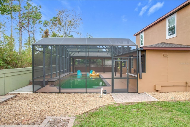 back of property with glass enclosure and a patio area