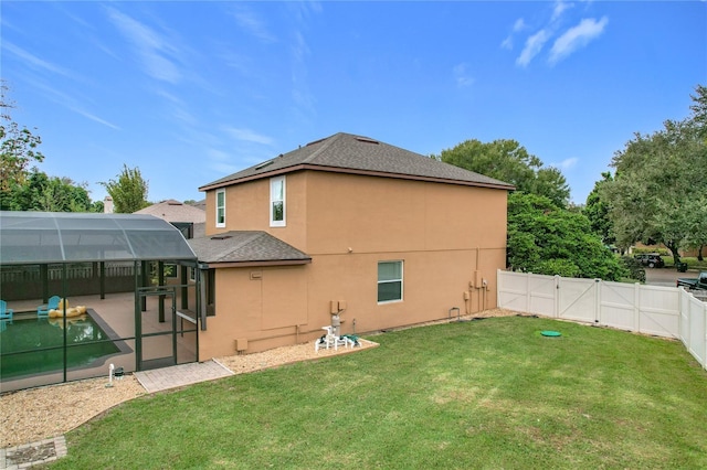 rear view of property featuring a lawn, glass enclosure, a patio area, and a swimming pool