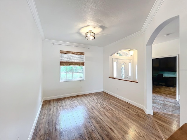 spare room with wood-type flooring, a textured ceiling, and crown molding