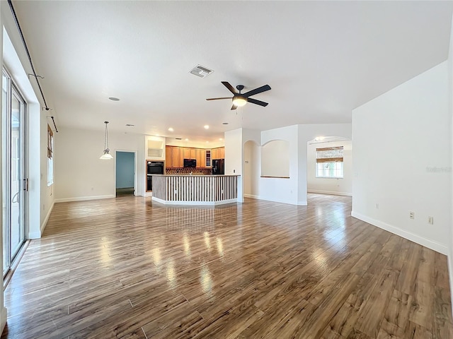 unfurnished living room featuring ceiling fan and wood-type flooring