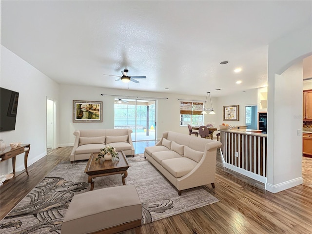 living room with a textured ceiling, hardwood / wood-style flooring, and ceiling fan