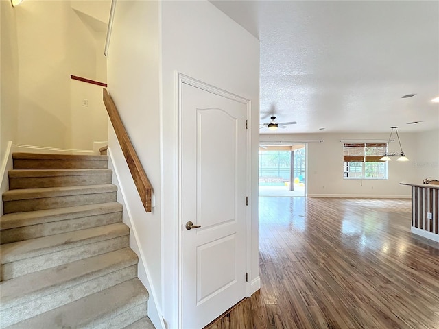 staircase featuring hardwood / wood-style floors, ceiling fan, and a textured ceiling