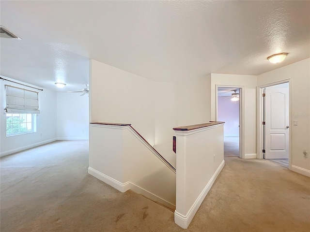 hall featuring light carpet and a textured ceiling