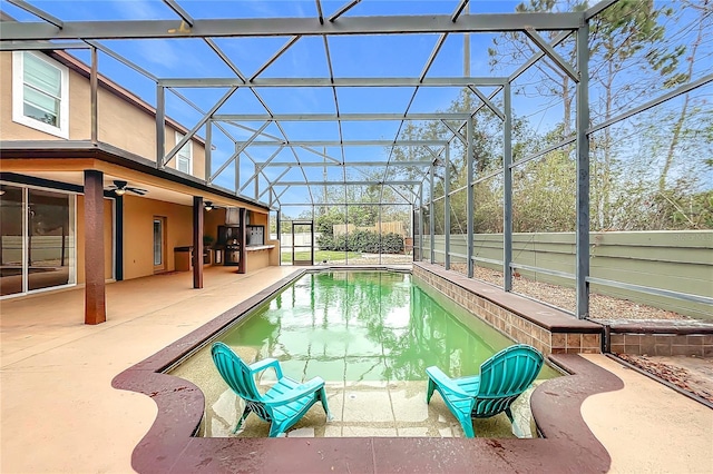 view of swimming pool with glass enclosure, ceiling fan, and a patio