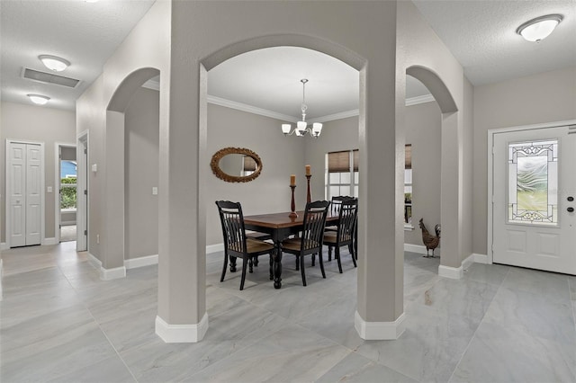 dining area featuring crown molding, a textured ceiling, and a notable chandelier