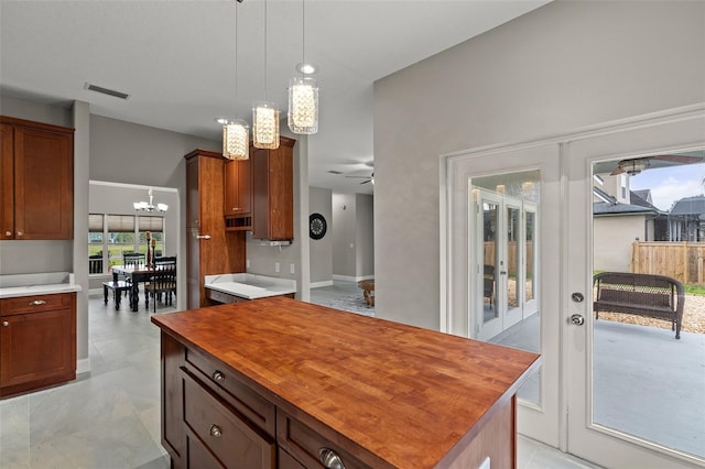 kitchen with french doors, wooden counters, pendant lighting, a kitchen island, and ceiling fan with notable chandelier