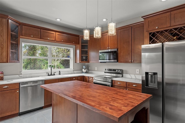 kitchen with sink, a center island, wooden counters, pendant lighting, and appliances with stainless steel finishes