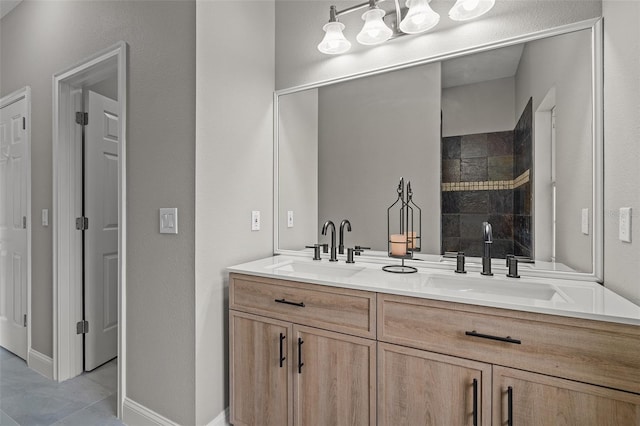 bathroom with tile patterned flooring, a tile shower, and vanity