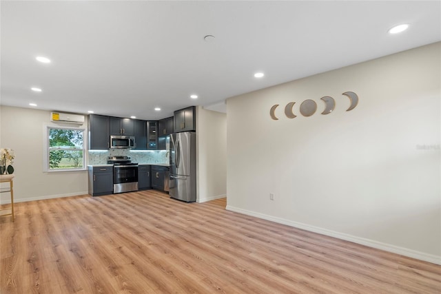 kitchen with a wall mounted air conditioner, light wood-type flooring, stainless steel appliances, and tasteful backsplash