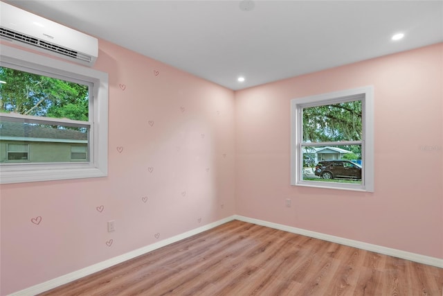 unfurnished room with an AC wall unit and light hardwood / wood-style floors