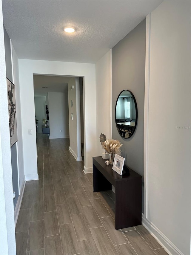 hall with baseboards and a textured ceiling