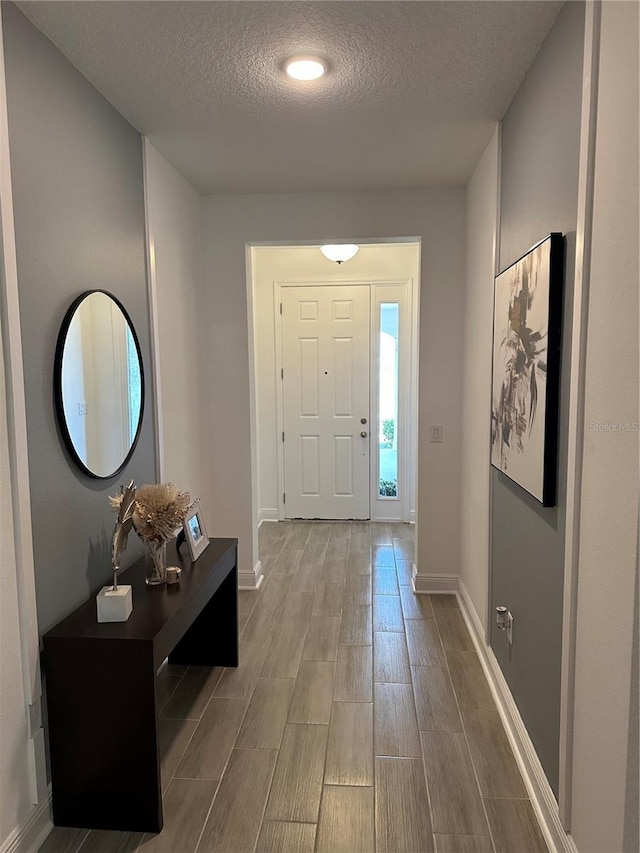 entryway featuring wood tiled floor, a textured ceiling, and baseboards