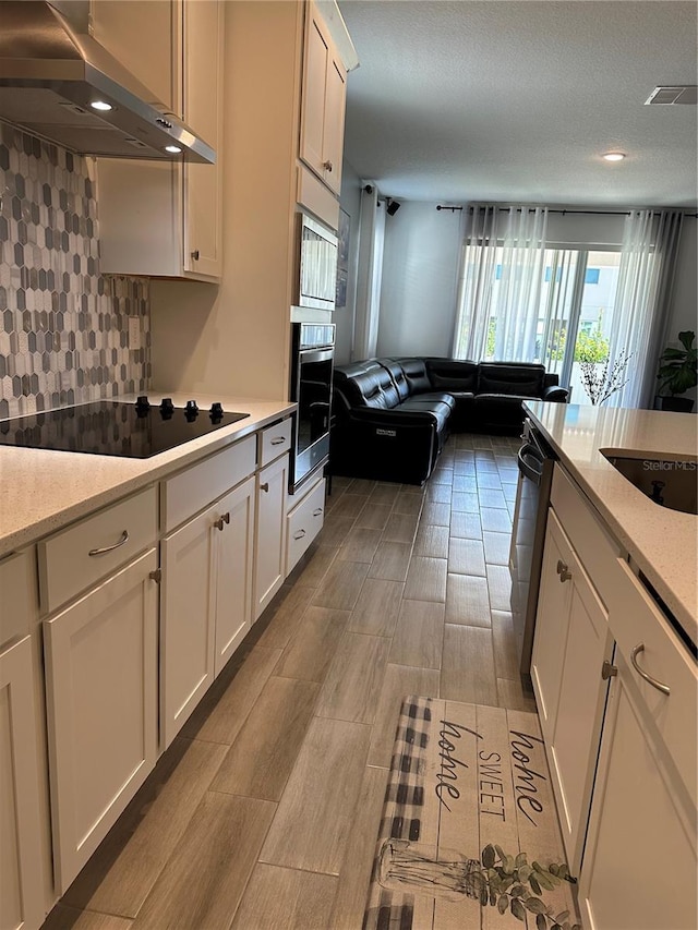 kitchen featuring light countertops, appliances with stainless steel finishes, ventilation hood, and white cabinets