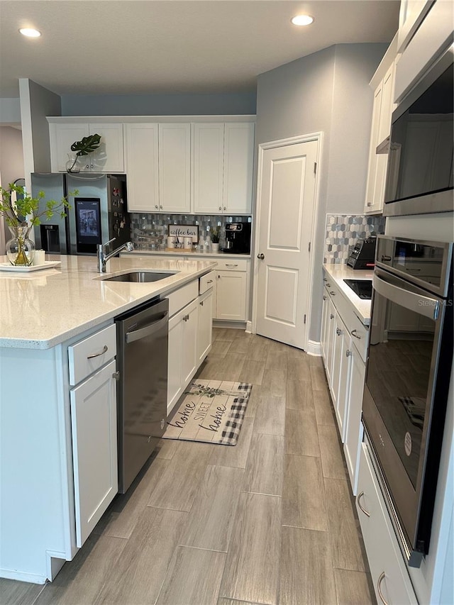 kitchen featuring stainless steel appliances, recessed lighting, backsplash, white cabinets, and a sink