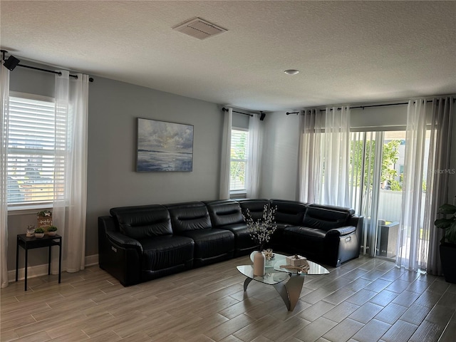 living area featuring wood finish floors, visible vents, and a textured ceiling