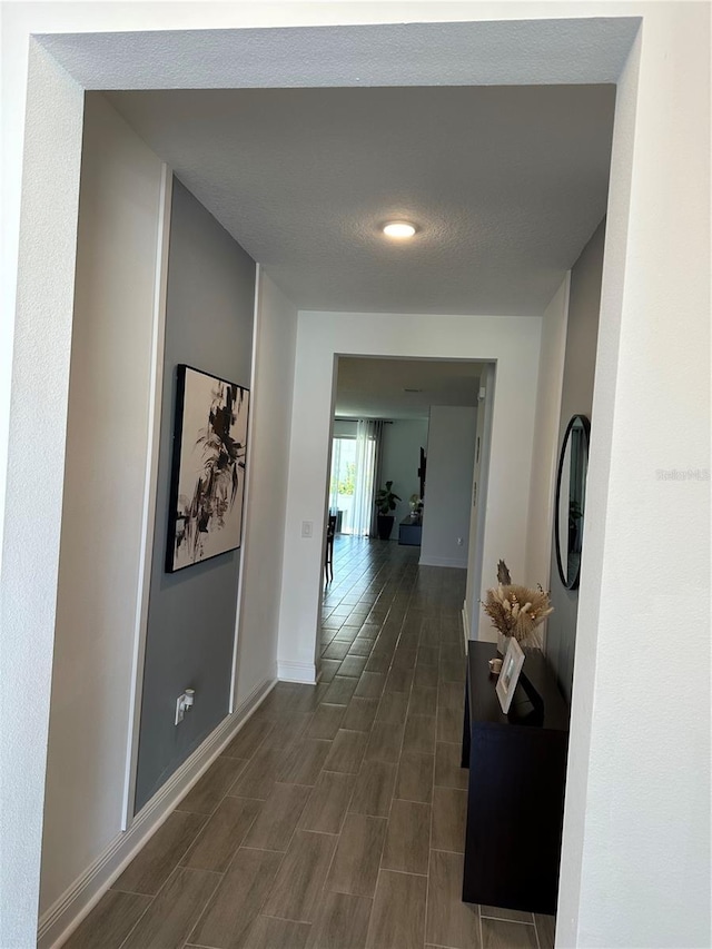 corridor featuring a textured ceiling and baseboards