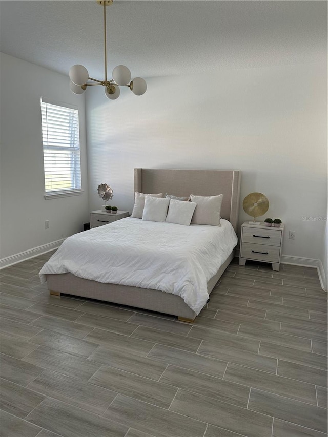 bedroom featuring wood finish floors, a textured ceiling, and baseboards