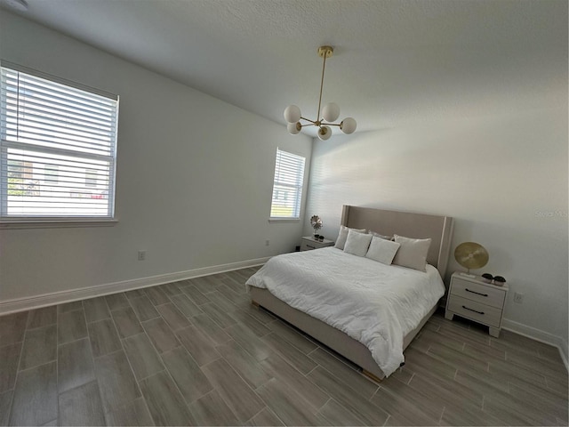 bedroom with wood finish floors, baseboards, and an inviting chandelier