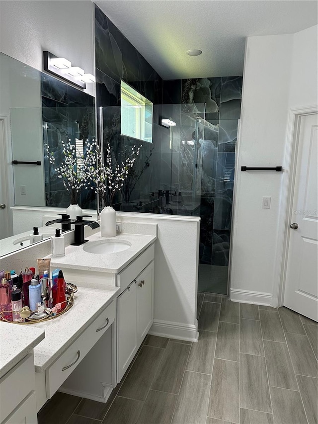 full bath featuring a marble finish shower and vanity