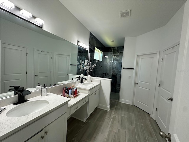 full bath with double vanity, a marble finish shower, visible vents, and a sink