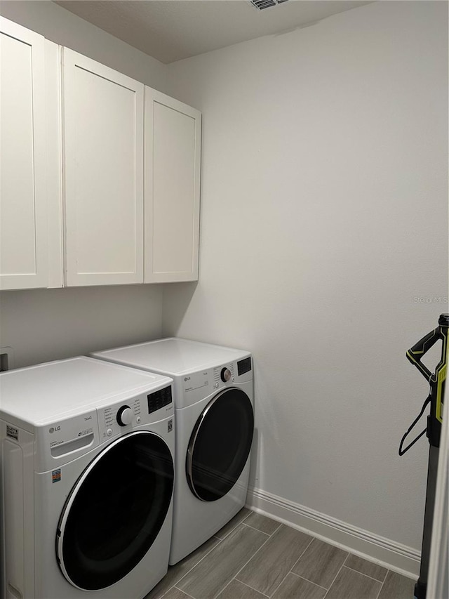 laundry room featuring wood finish floors, visible vents, baseboards, cabinet space, and washer and clothes dryer