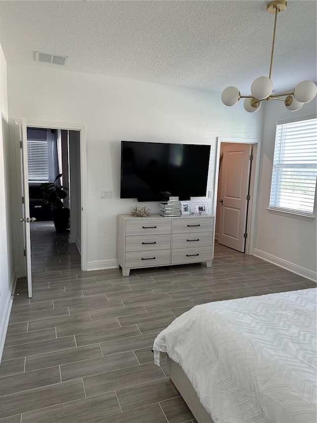 bedroom with a textured ceiling, wood finish floors, and visible vents