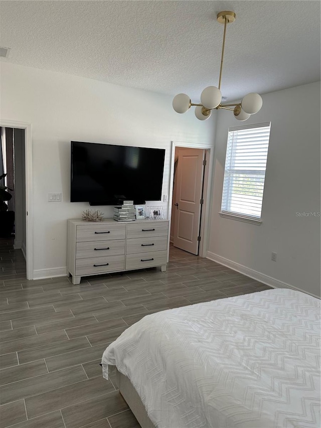 bedroom with baseboards, a textured ceiling, and wood finish floors