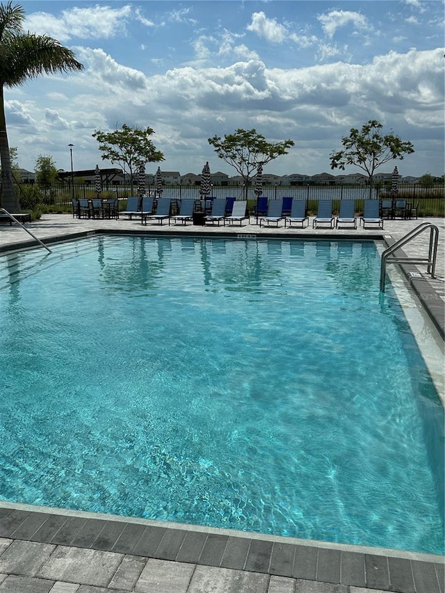 pool with a patio area and fence