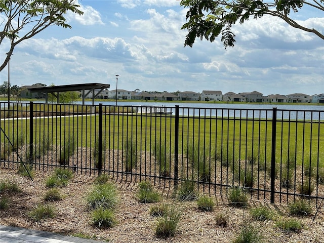 view of yard featuring a residential view, a water view, and fence